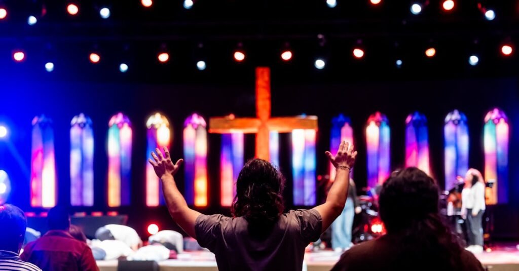 Lively church service with congregation worshipping under colorful stained-glass lighting.